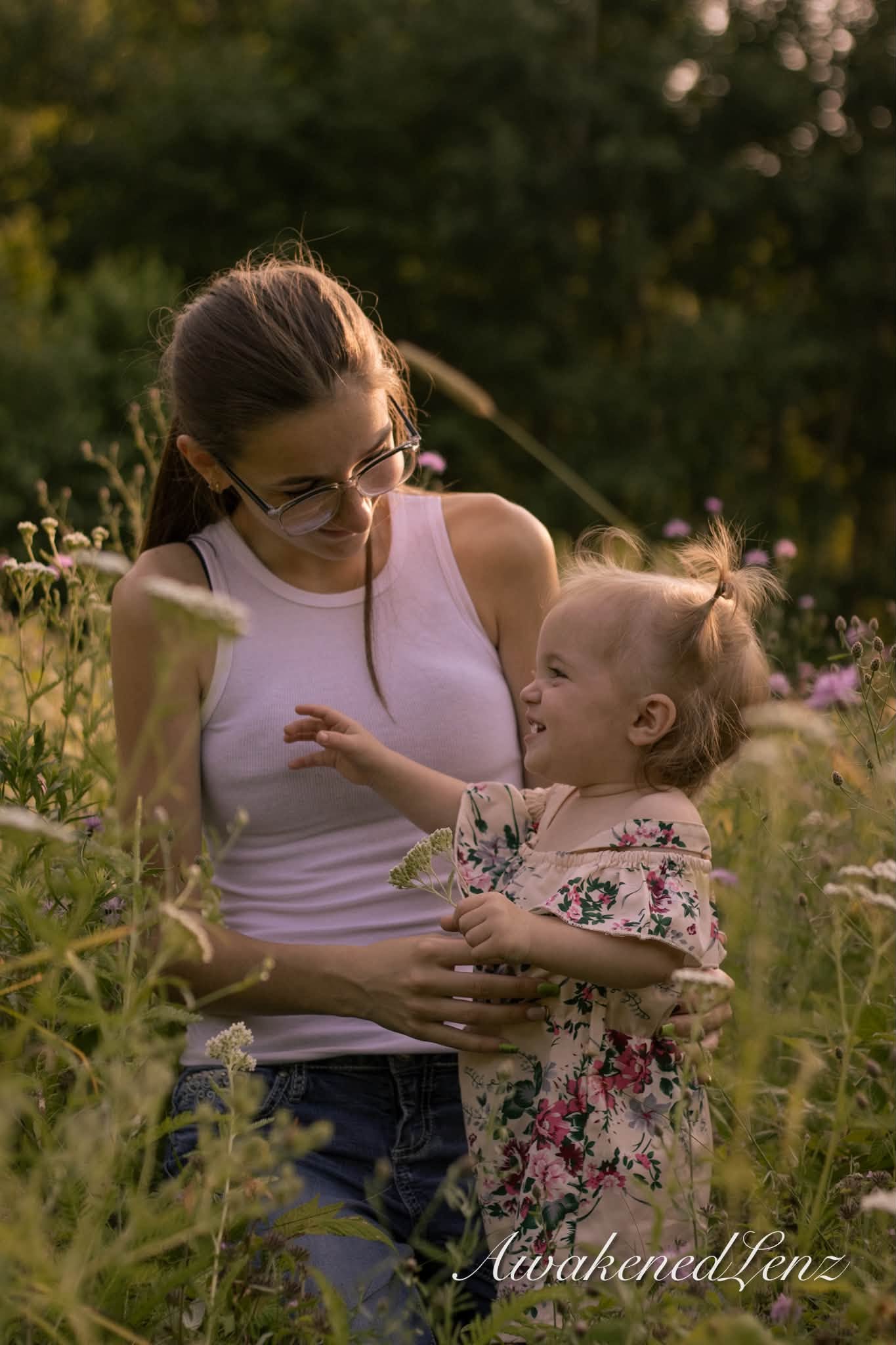 A woman holding her toddler niece in a sunlit meadow