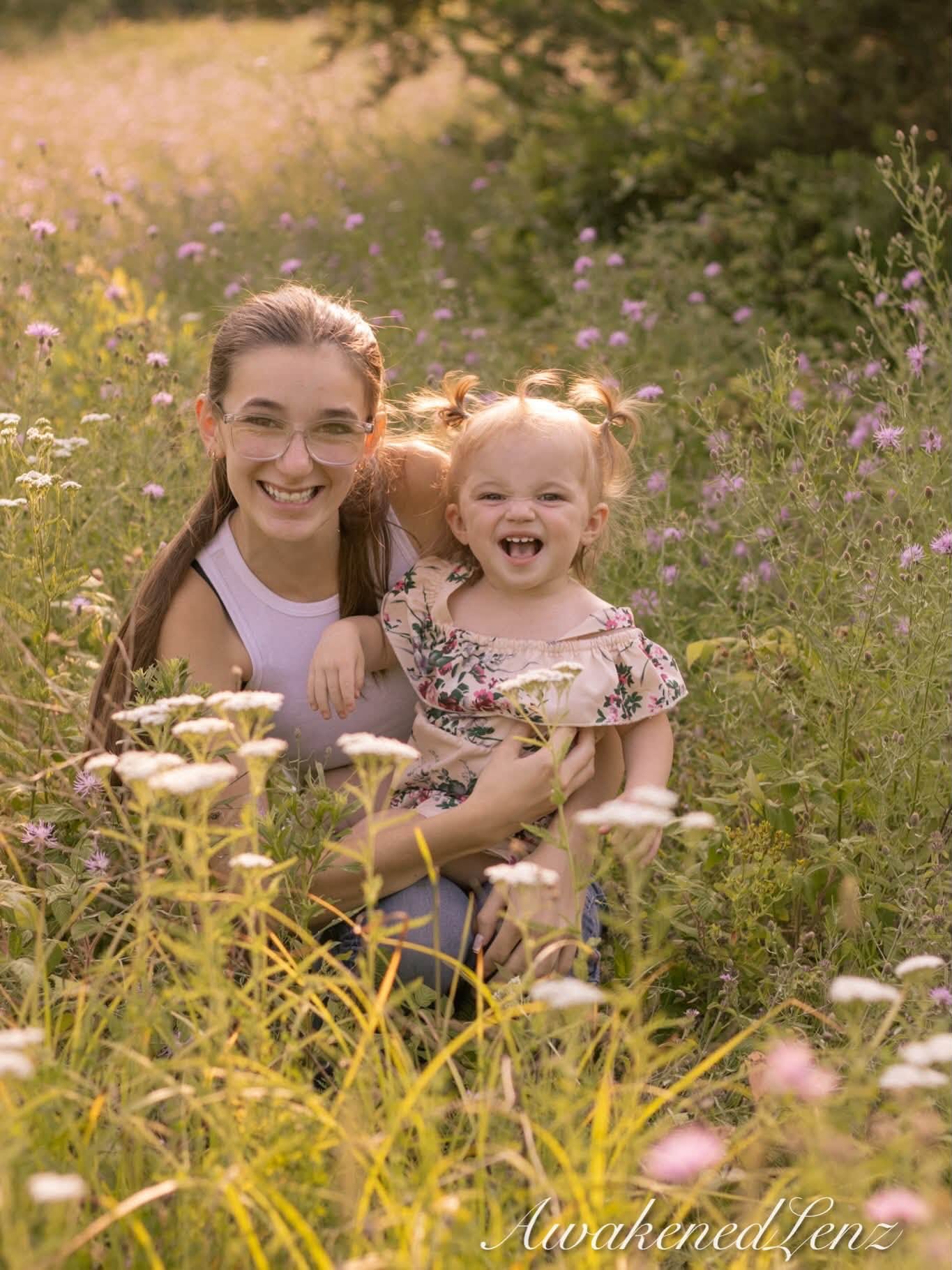 A woman and her toddler niece cheek to cheek among tall wildflowers