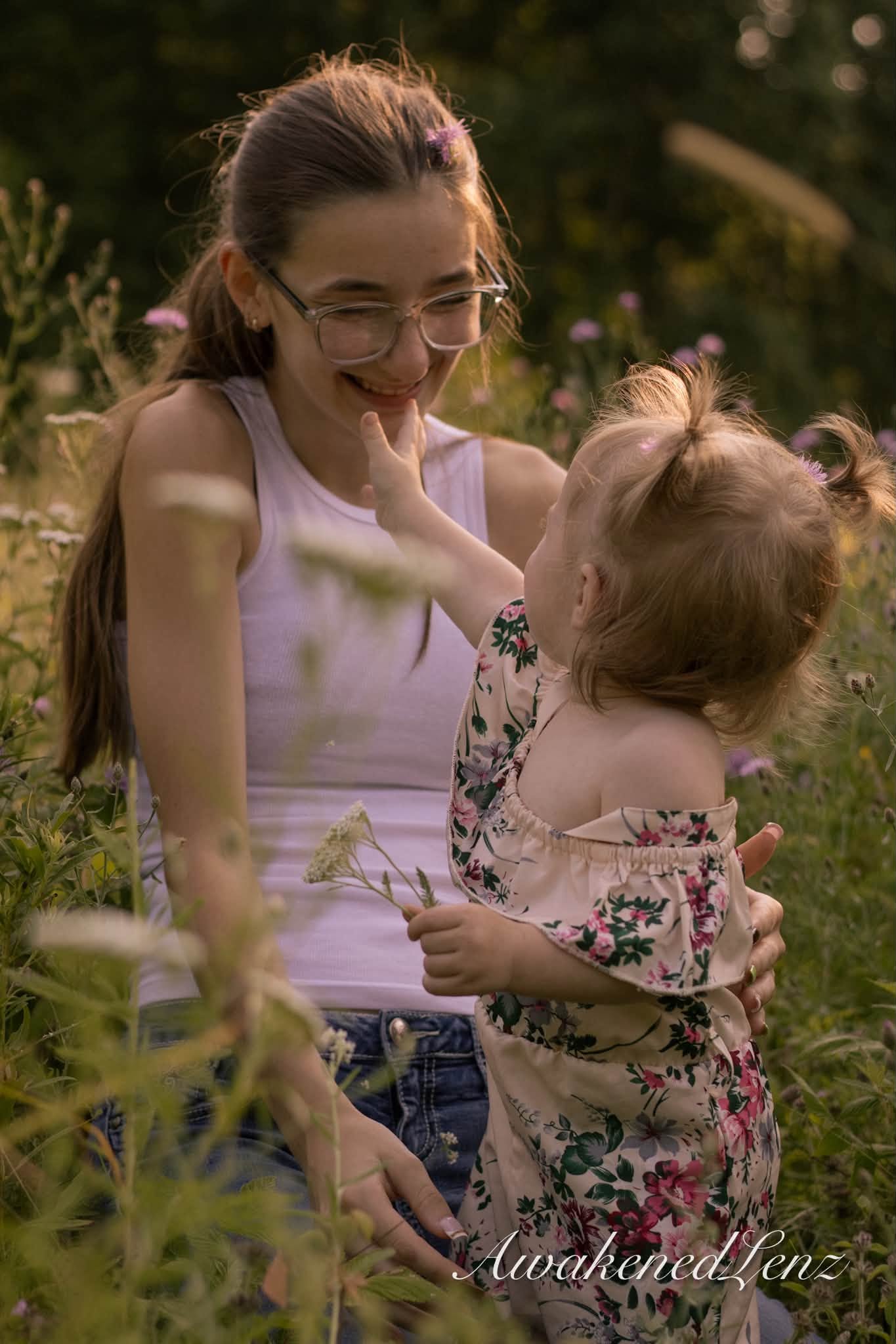 A woman laughing with her toddler niece on her hip in a summer field
