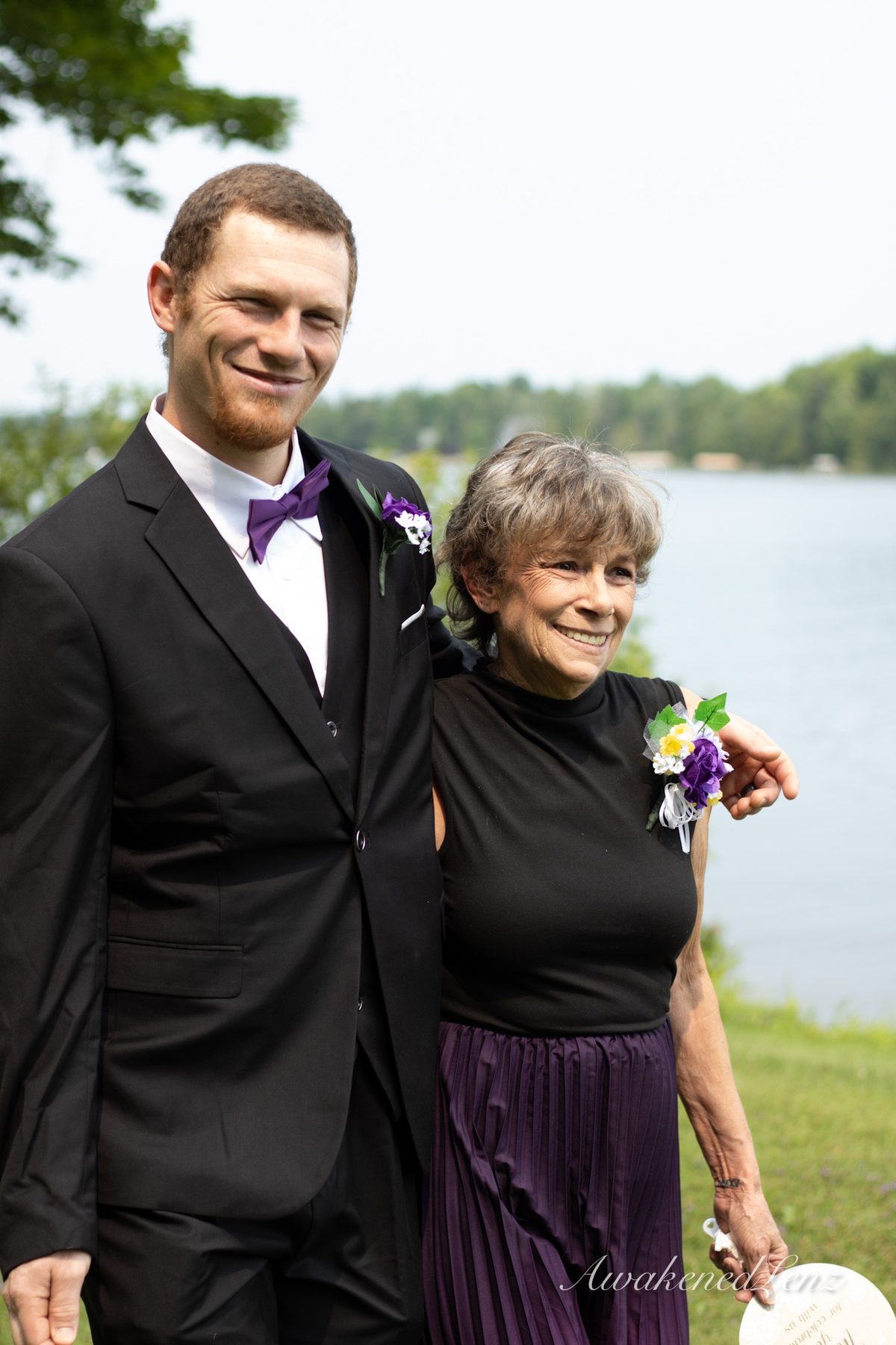 A groom standing with an older family member by the water