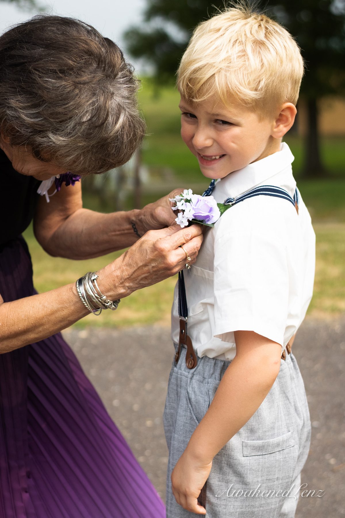 A grandmother pinning a boutonniere to a young ring bearer
