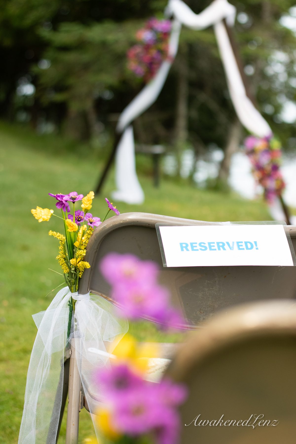 A reserved sign and wildflowers marking a seat at an outdoor ceremony