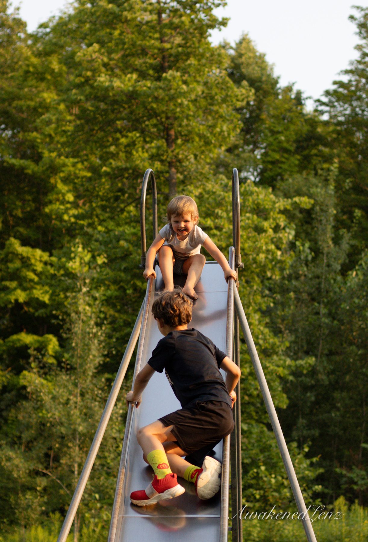 A father and his daughters playing at a park, frame 1 of 2