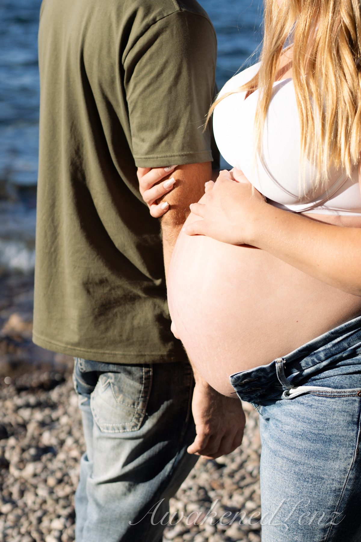 A maternity session on a rocky lakeshore at golden hour, frame 1 of 45