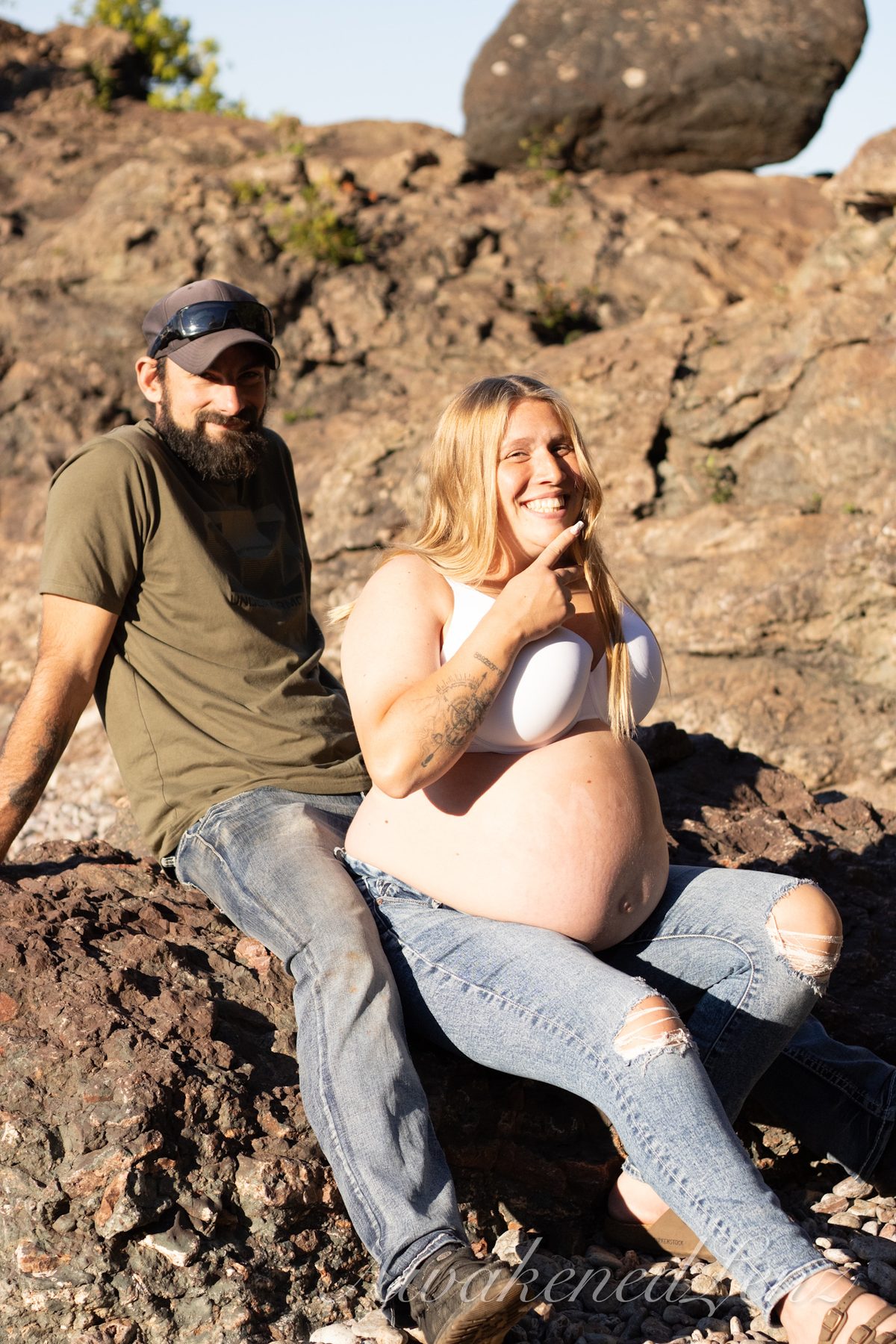 A maternity session on a rocky lakeshore at golden hour, frame 5 of 45