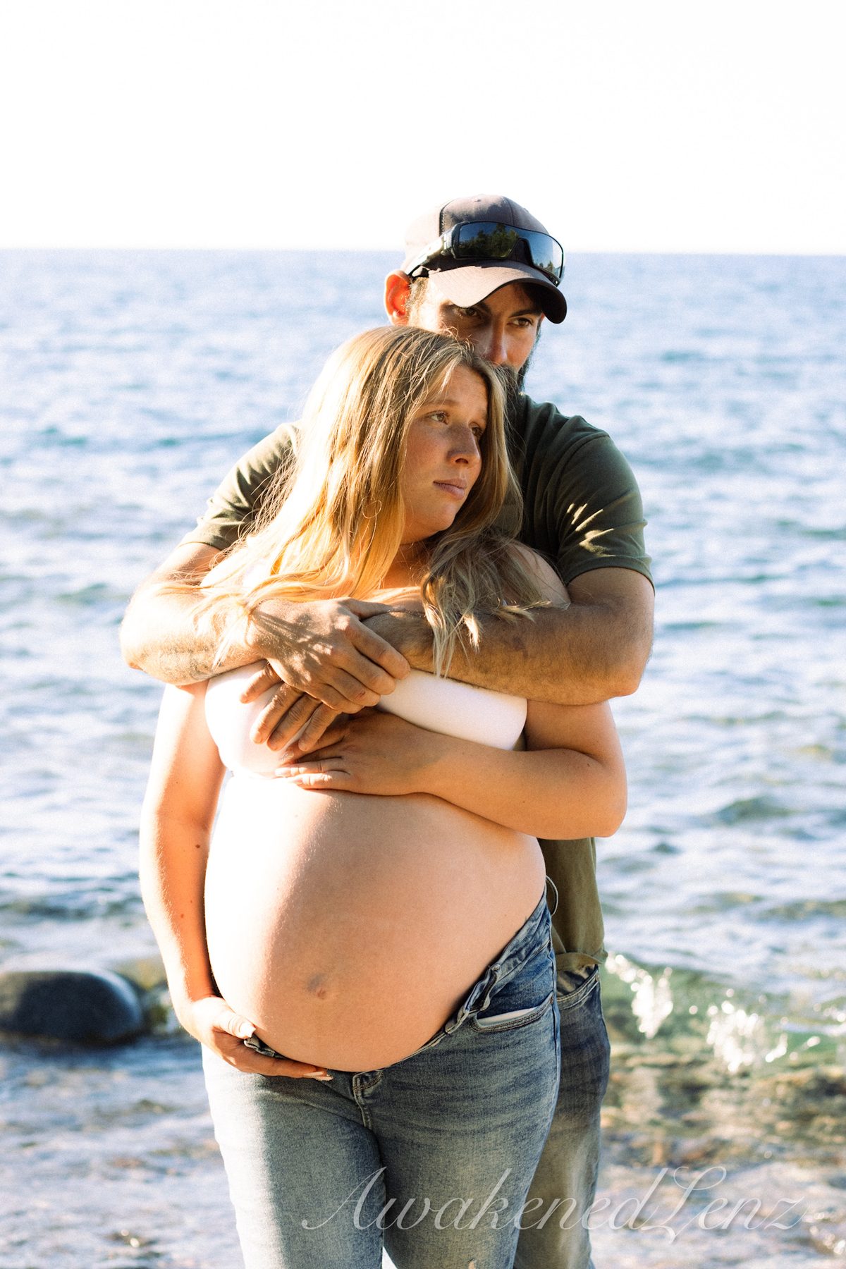 A maternity session on a rocky lakeshore at golden hour, frame 7 of 45