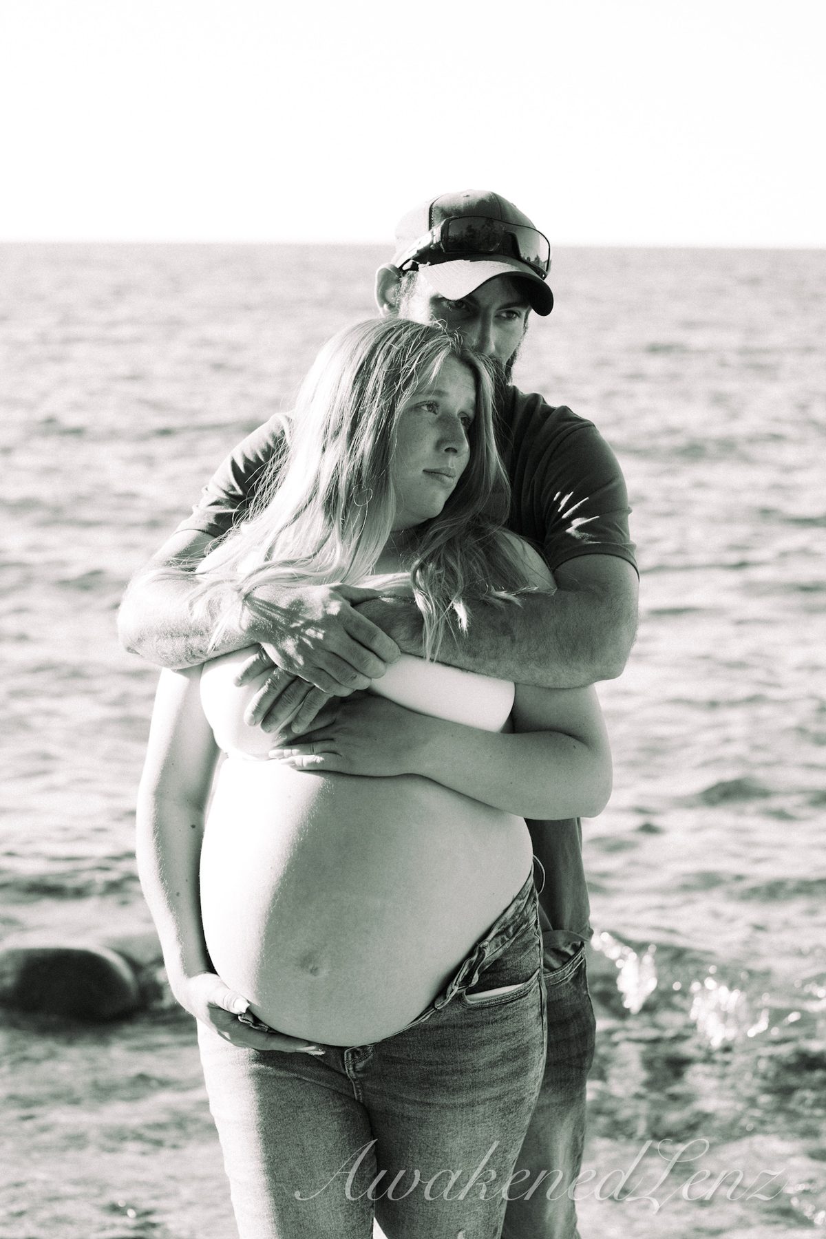 A maternity session on a rocky lakeshore at golden hour, frame 8 of 45