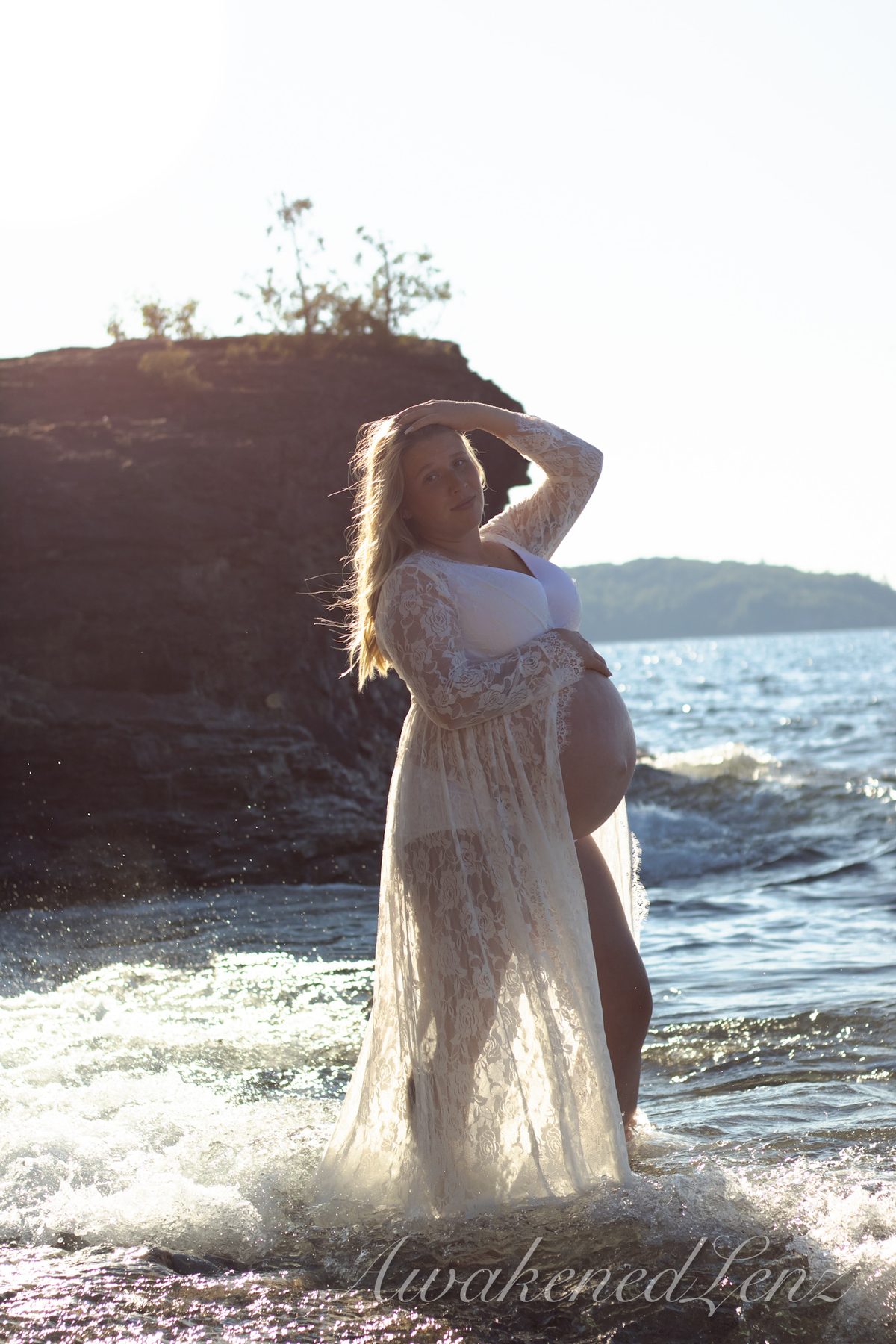 A maternity session on a rocky lakeshore at golden hour, frame 10 of 45