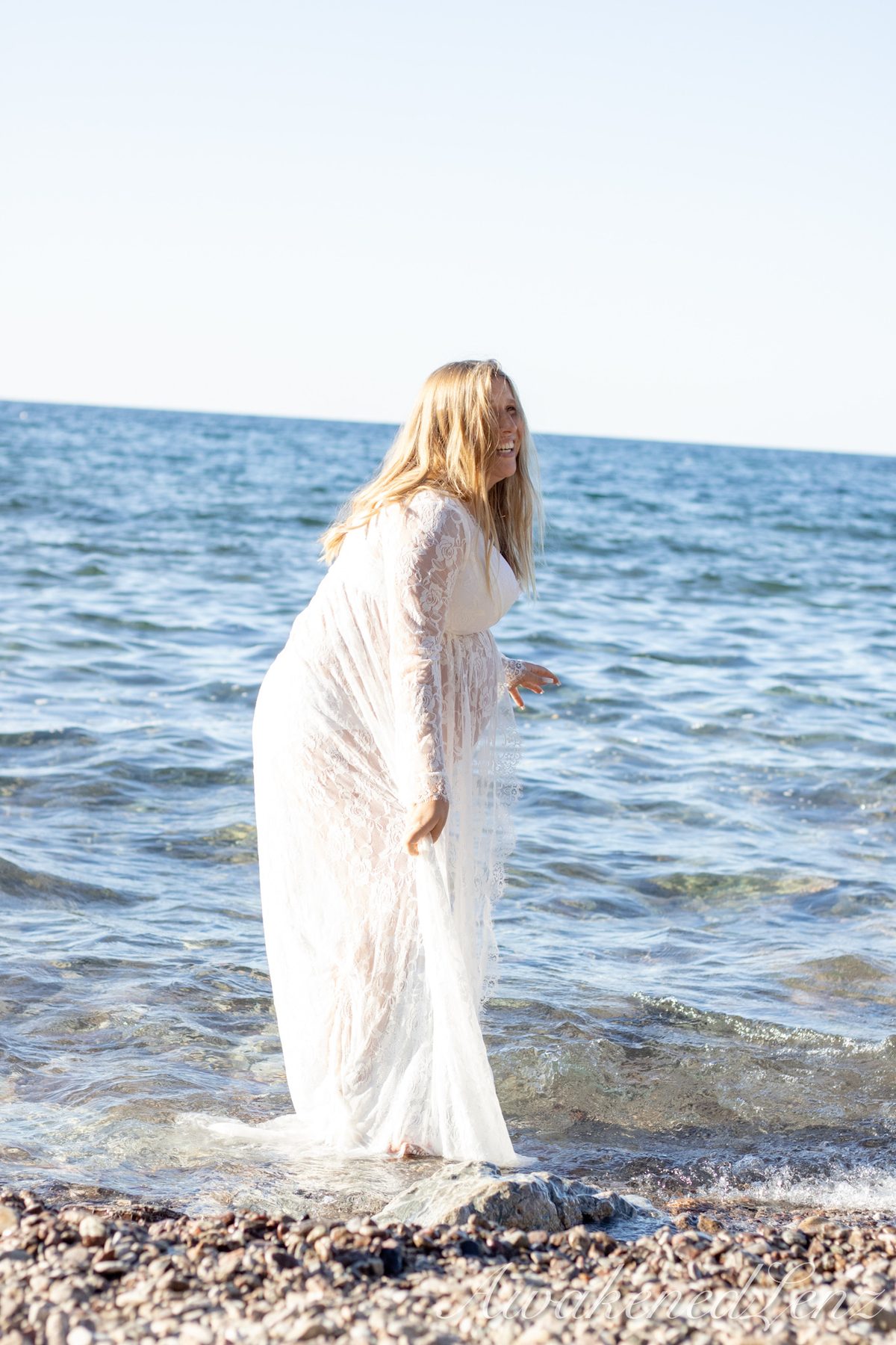 A maternity session on a rocky lakeshore at golden hour, frame 15 of 45