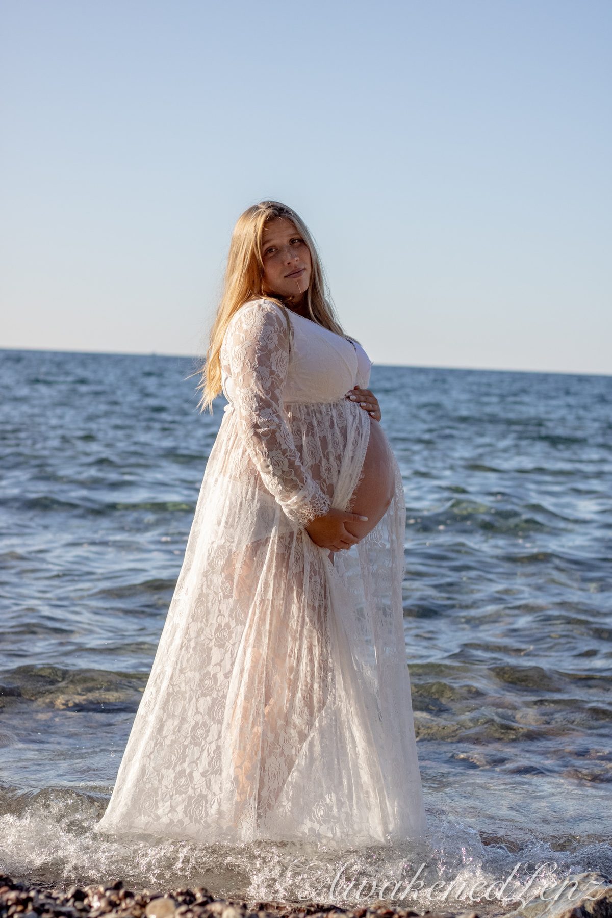 A maternity session on a rocky lakeshore at golden hour, frame 16 of 45