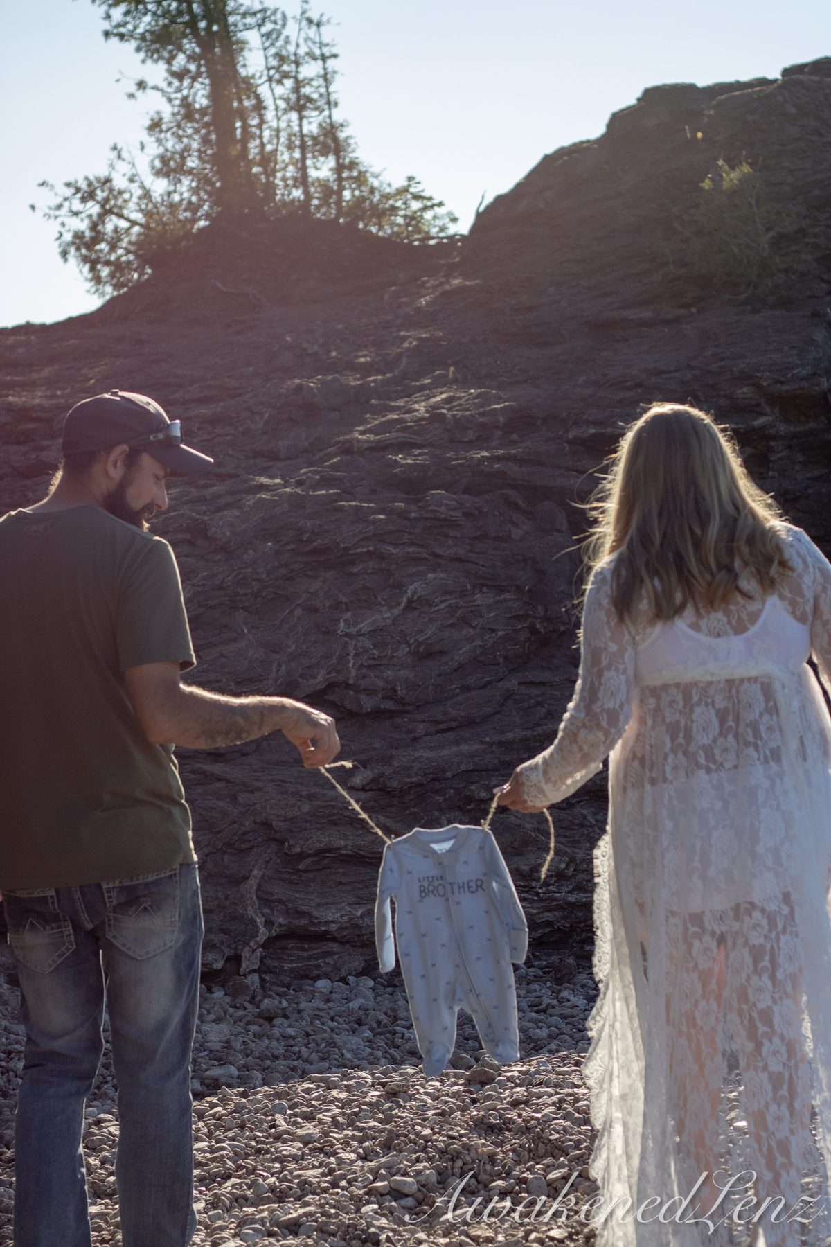 A maternity session on a rocky lakeshore at golden hour, frame 17 of 45