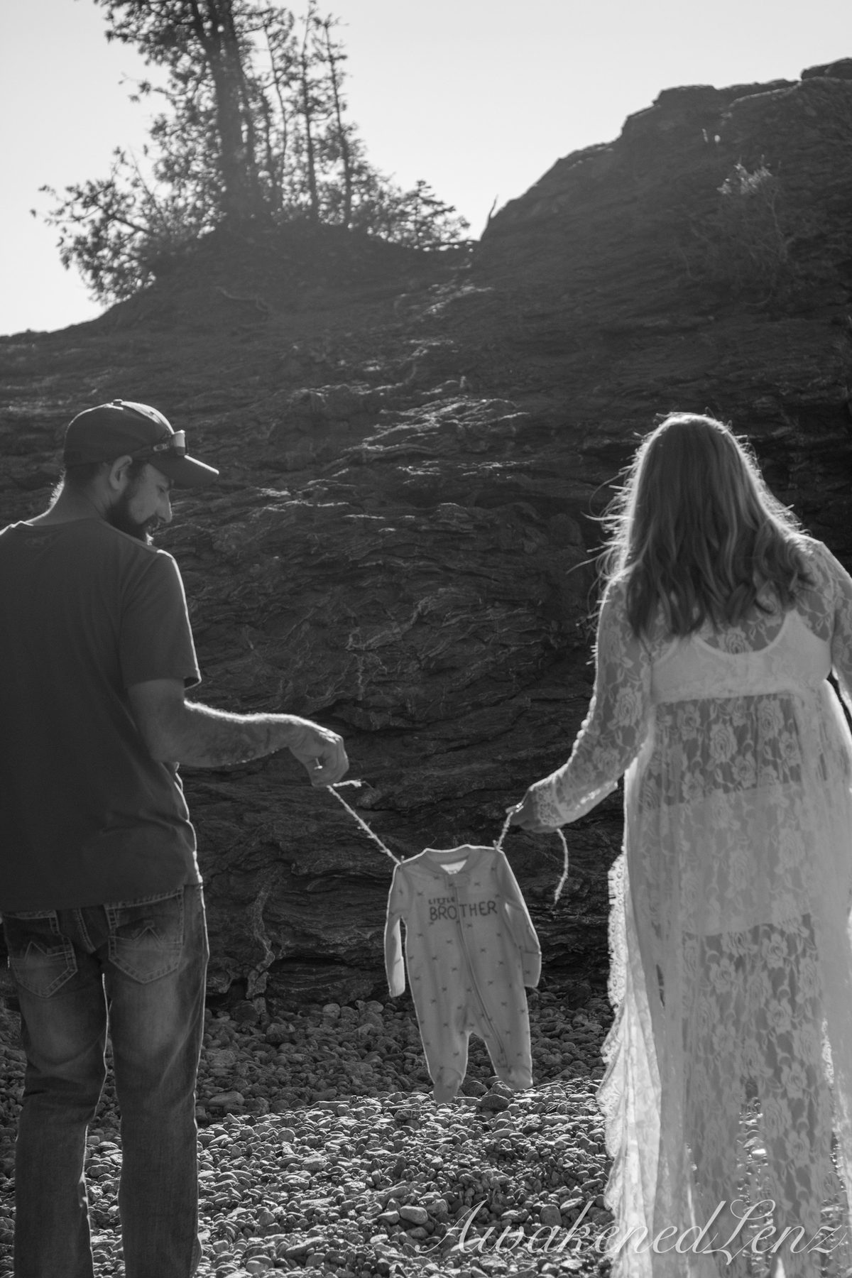 A maternity session on a rocky lakeshore at golden hour, frame 18 of 45