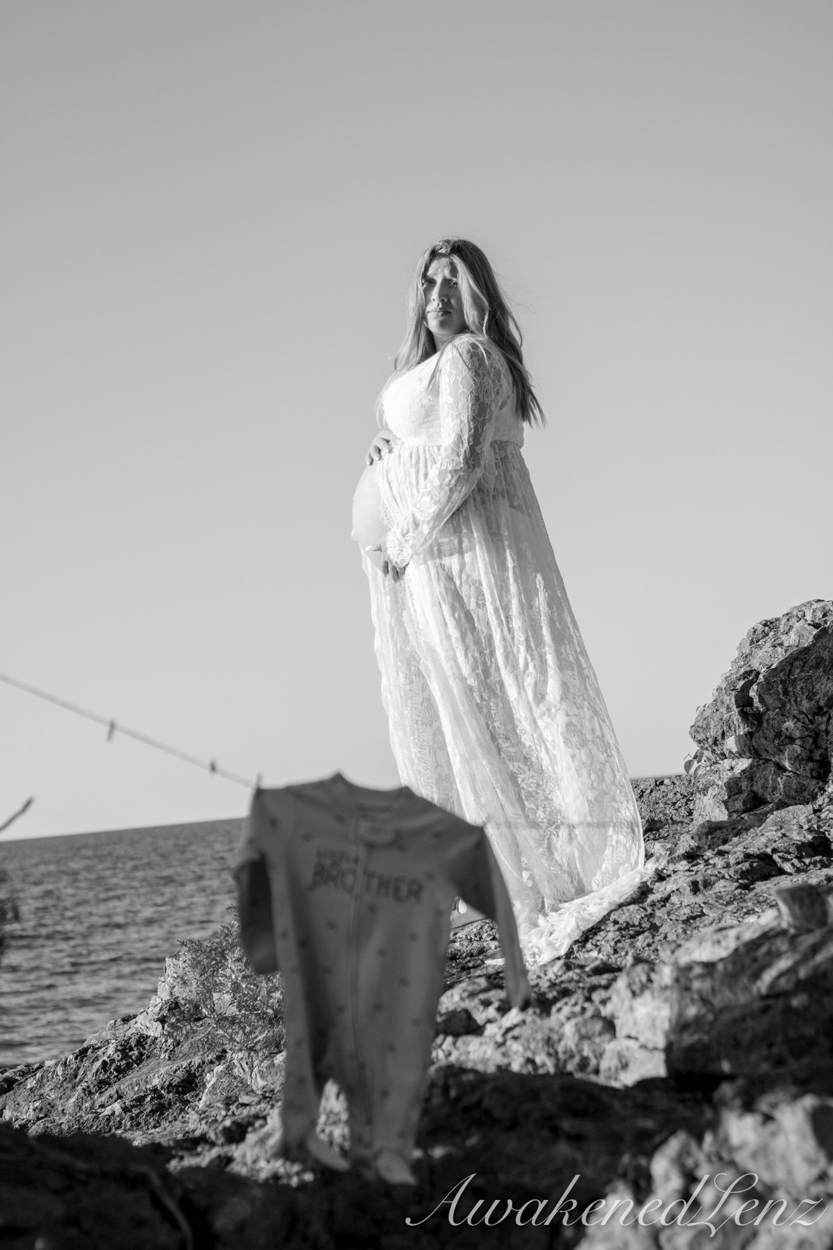A maternity session on a rocky lakeshore at golden hour, frame 20 of 45