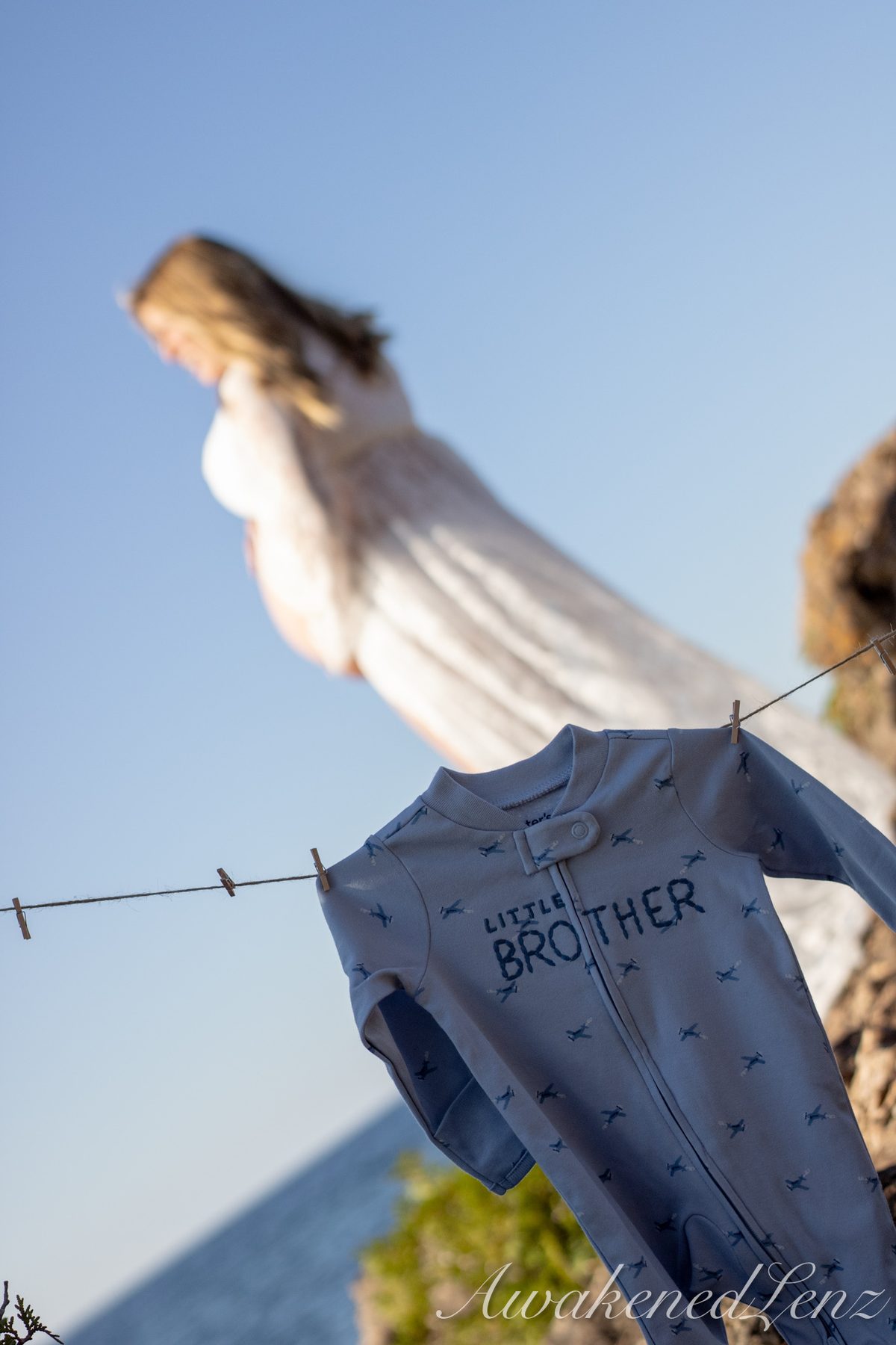 A maternity session on a rocky lakeshore at golden hour, frame 24 of 45