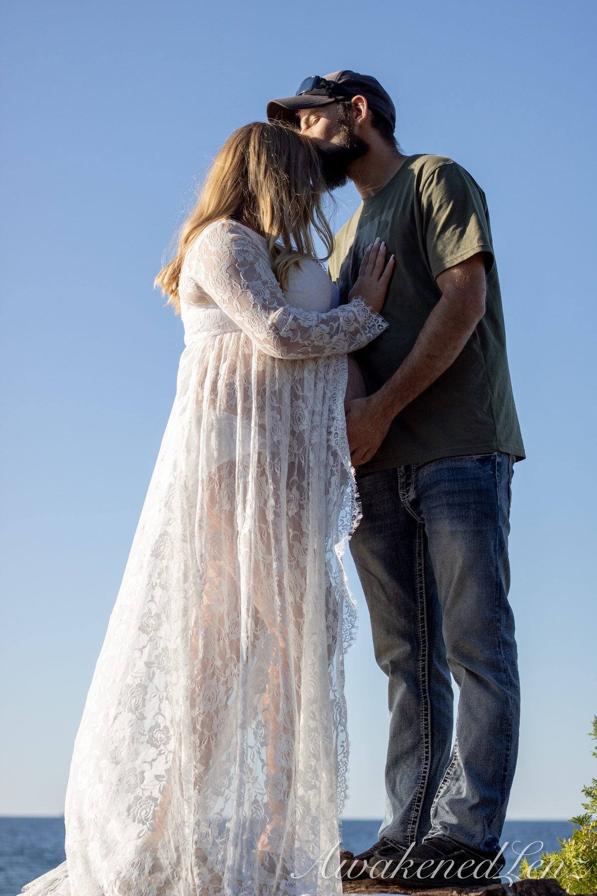 A maternity session on a rocky lakeshore at golden hour, frame 26 of 45