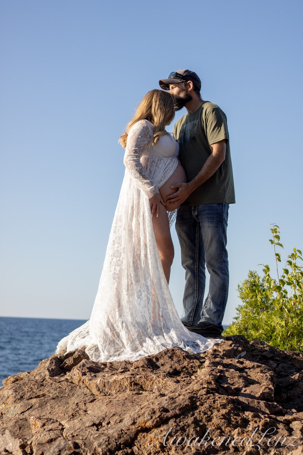 A maternity session on a rocky lakeshore at golden hour, frame 30 of 45