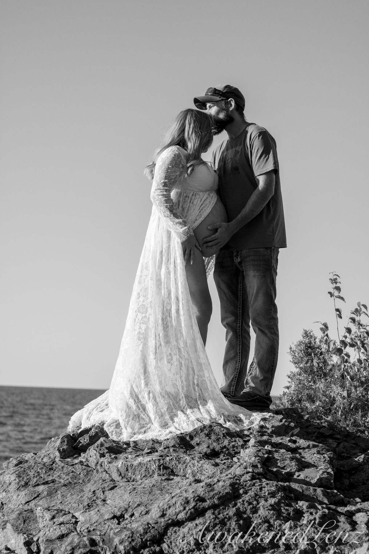 A maternity session on a rocky lakeshore at golden hour, frame 31 of 45