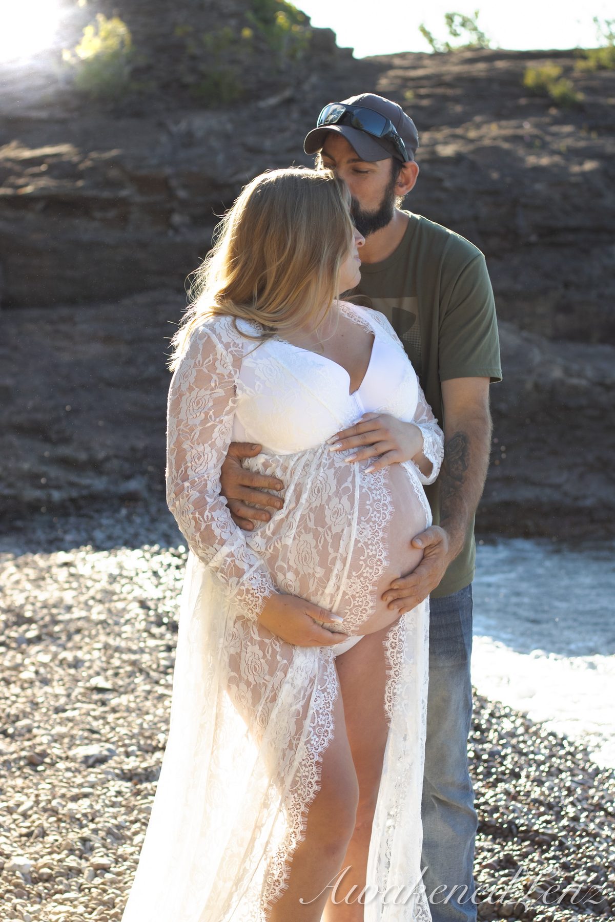 A maternity session on a rocky lakeshore at golden hour, frame 37 of 45