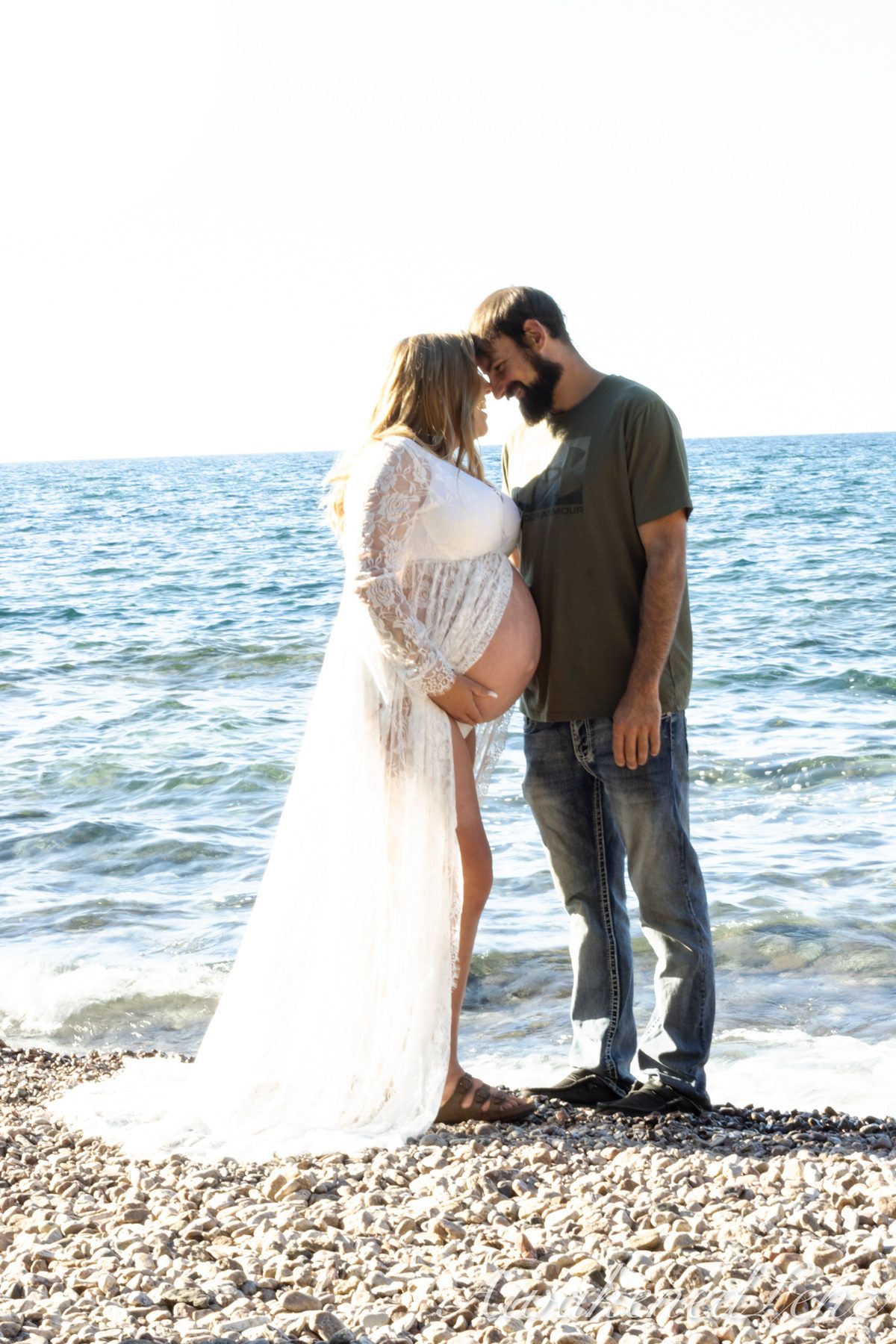 A maternity session on a rocky lakeshore at golden hour, frame 38 of 45