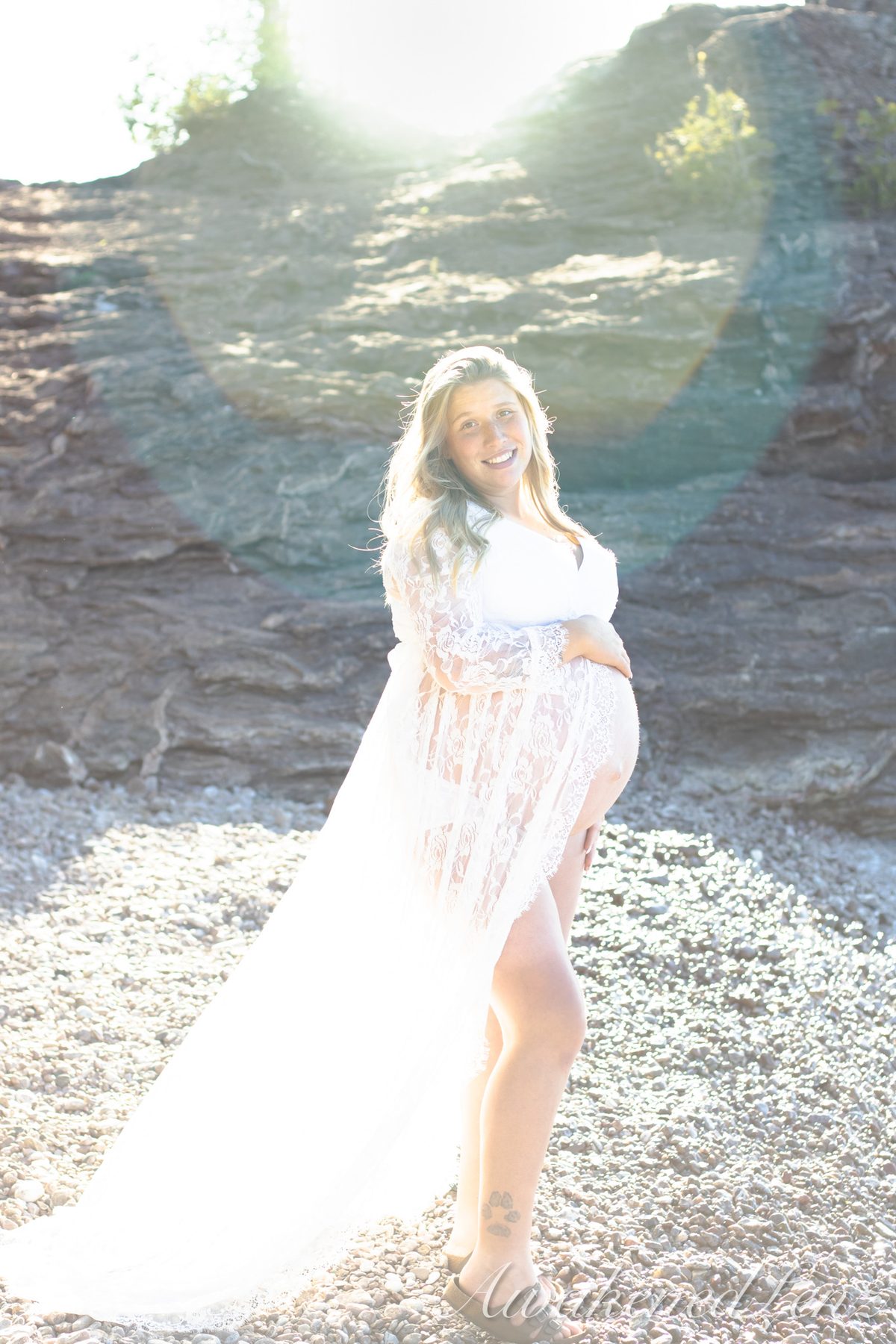 A maternity session on a rocky lakeshore at golden hour, frame 41 of 45