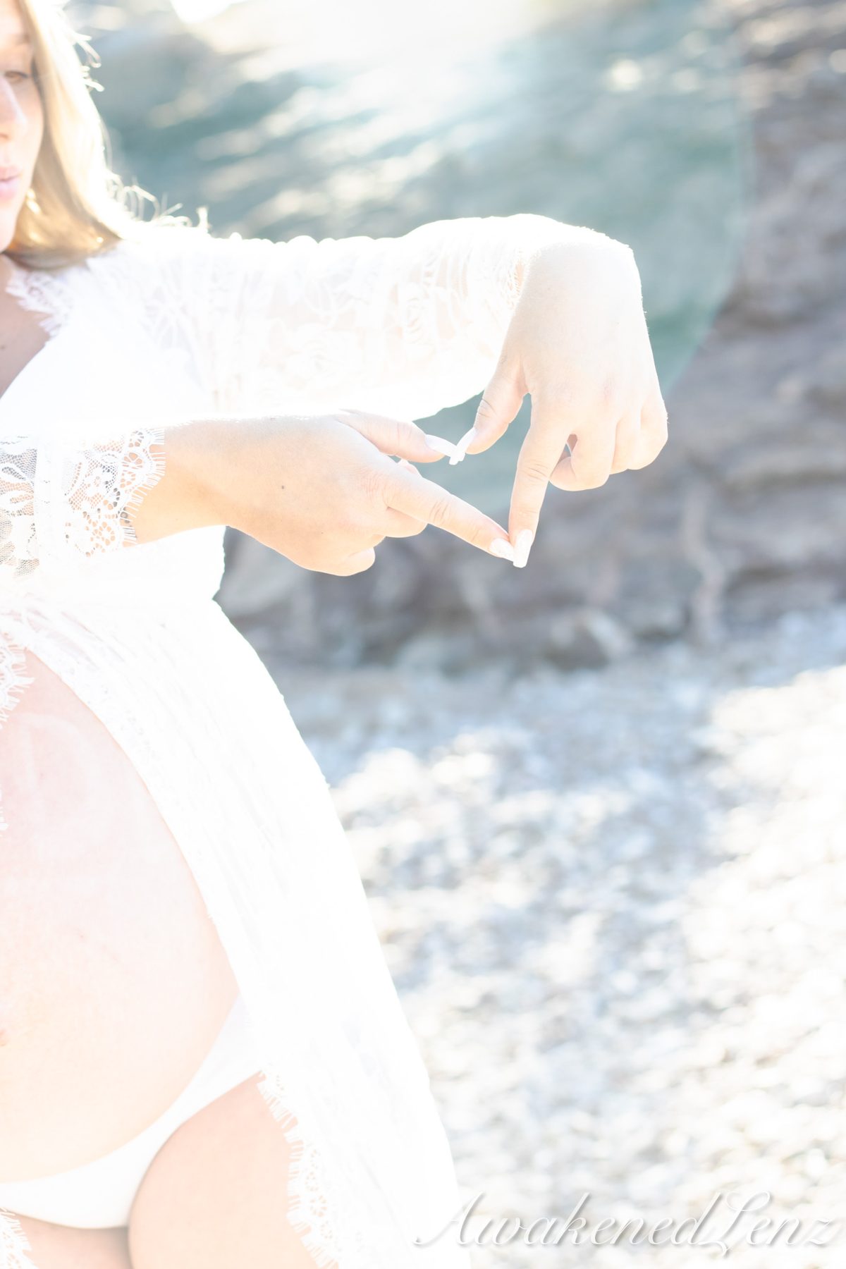 A maternity session on a rocky lakeshore at golden hour, frame 42 of 45