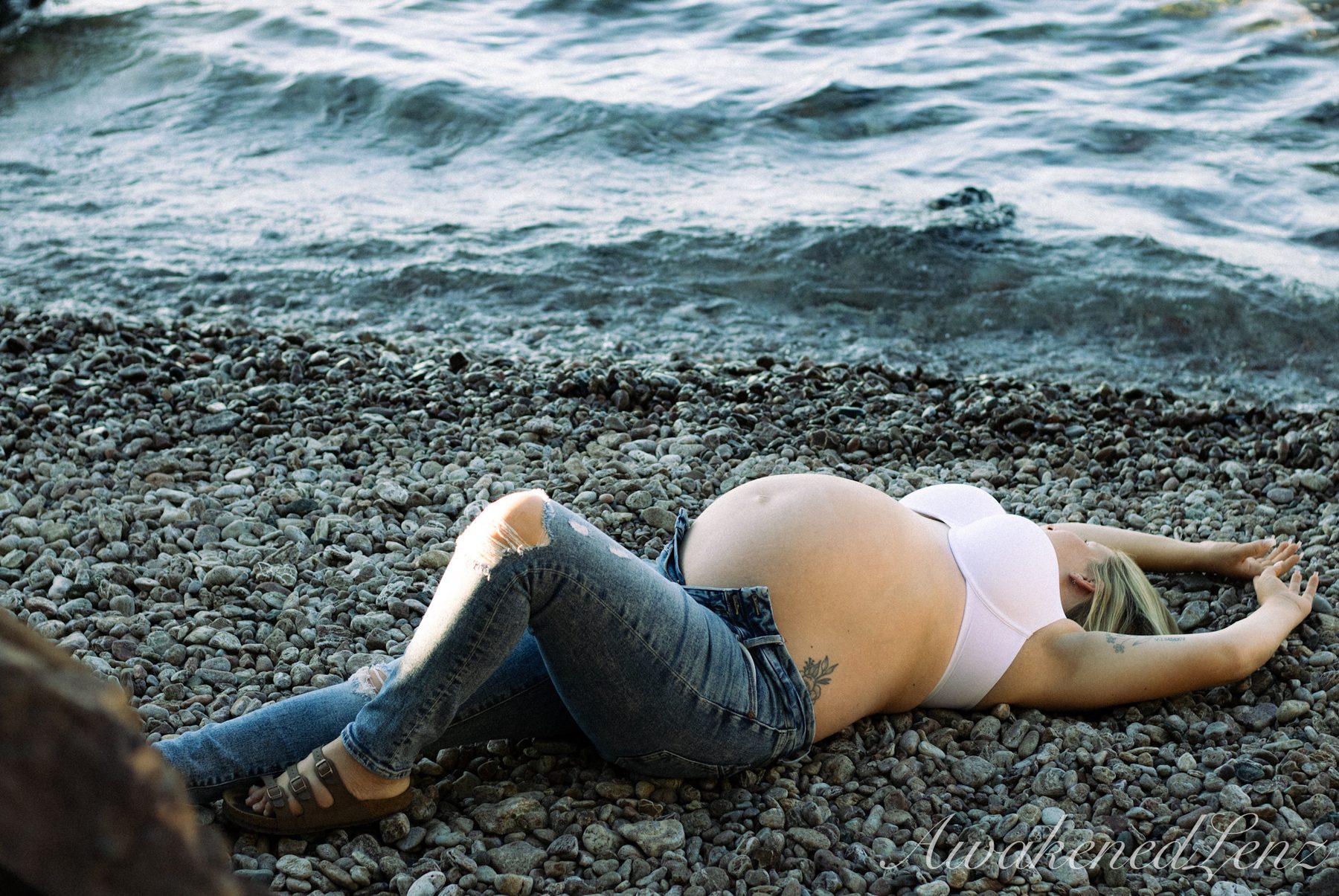 A maternity session on a rocky lakeshore at golden hour, frame 44 of 45